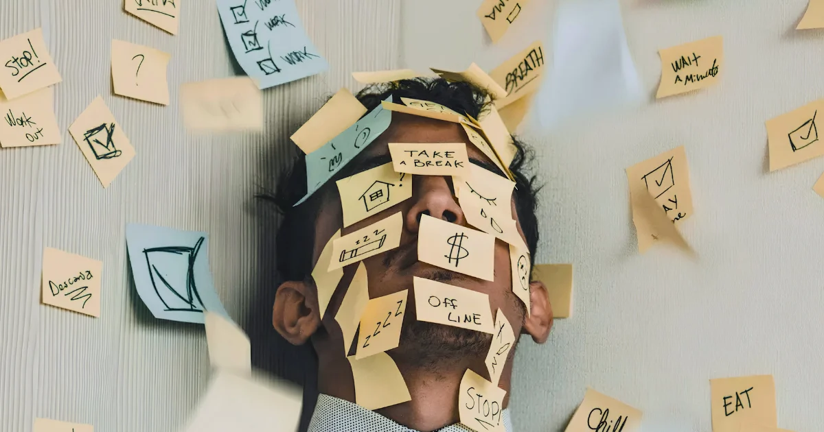 Person covered in sticky notes surrounded by reminders, symbolizing mental overload, stress, anxiety, and feeling overwhelmed.