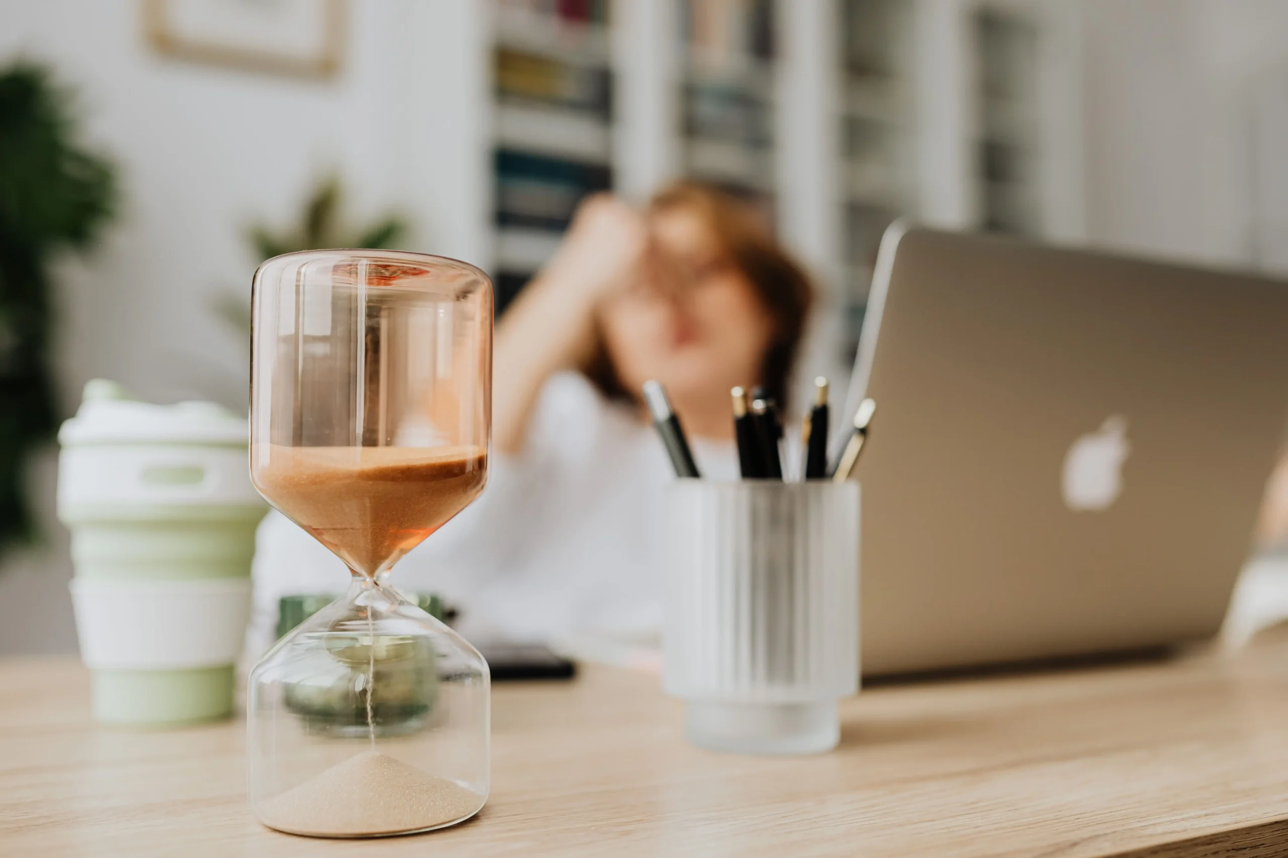 hourglass showing time passing fast while a woman is struggling with task paralysis.